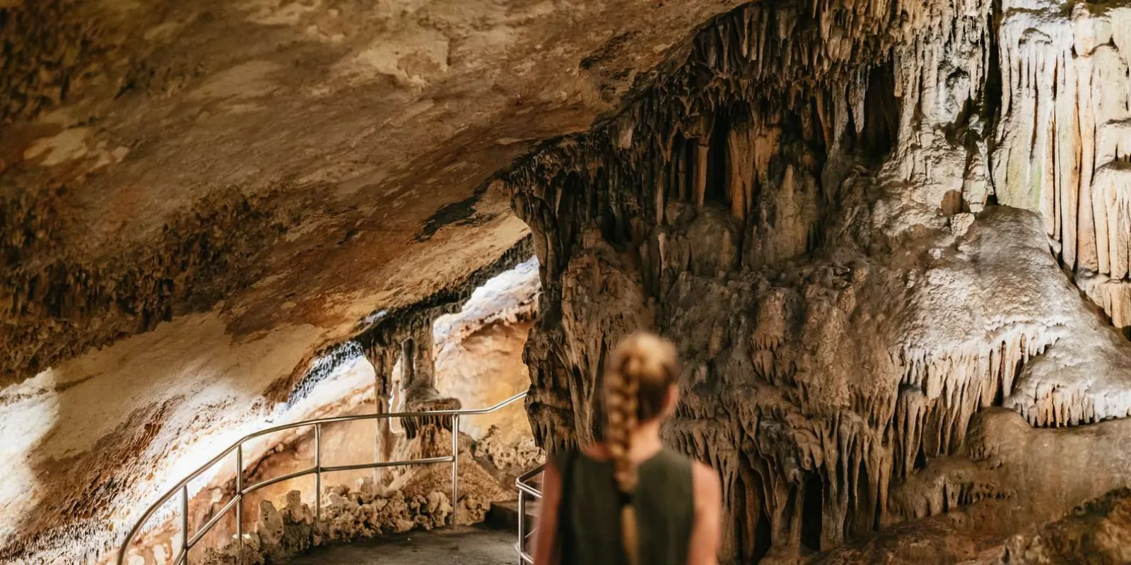 Caves of Drach visitor admiring stalactite formations at the cave entrance walkway — Mallorca