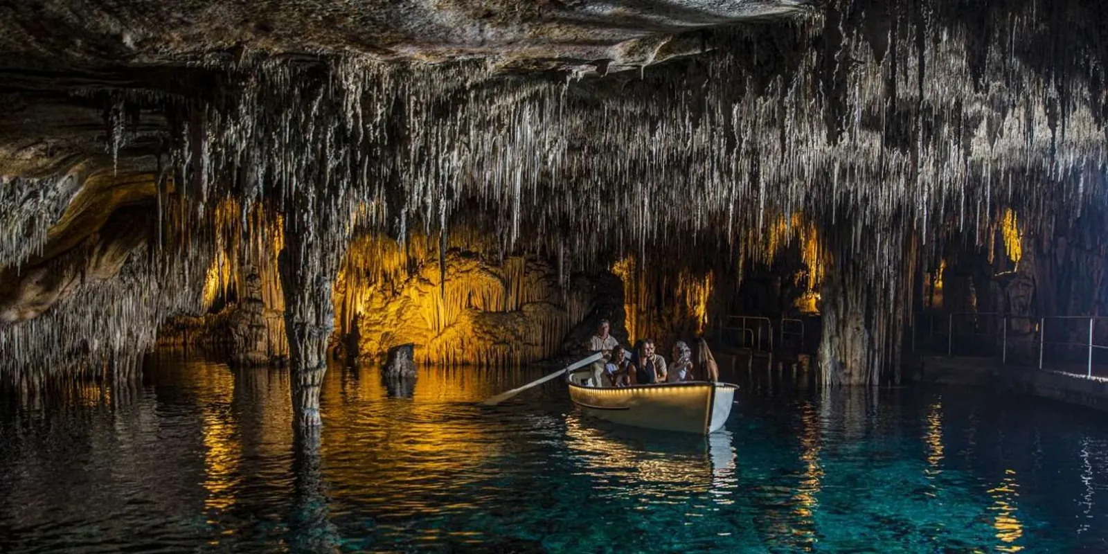 Caves of Drach rowboat gliding under a low stalactite ceiling on the turquoise Lake Martel — Mallorca