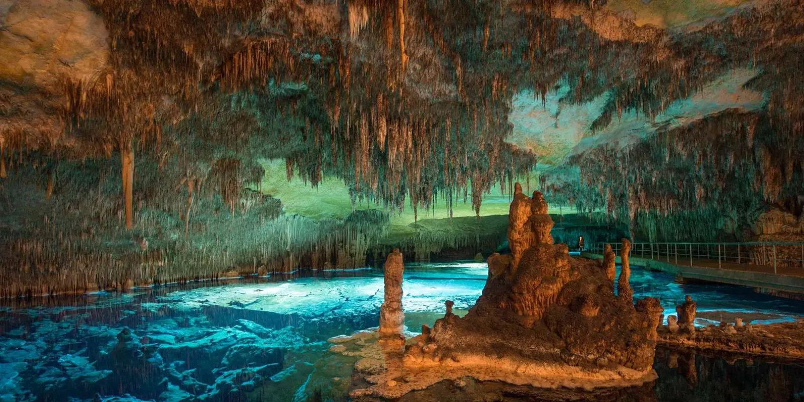Caves of Drach Lake Martel glowing teal under stalactite formations with coloured LED lighting — Mallorca